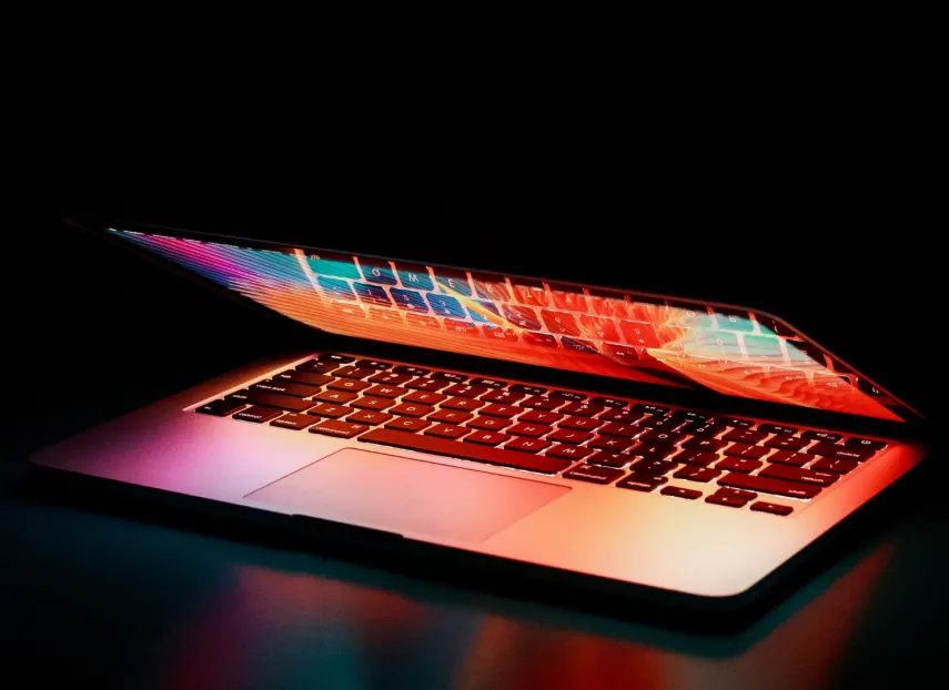 A partially open laptop glowing with neon light