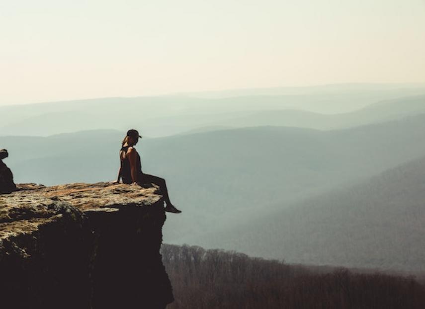A woman sitting on the edge of a cliff