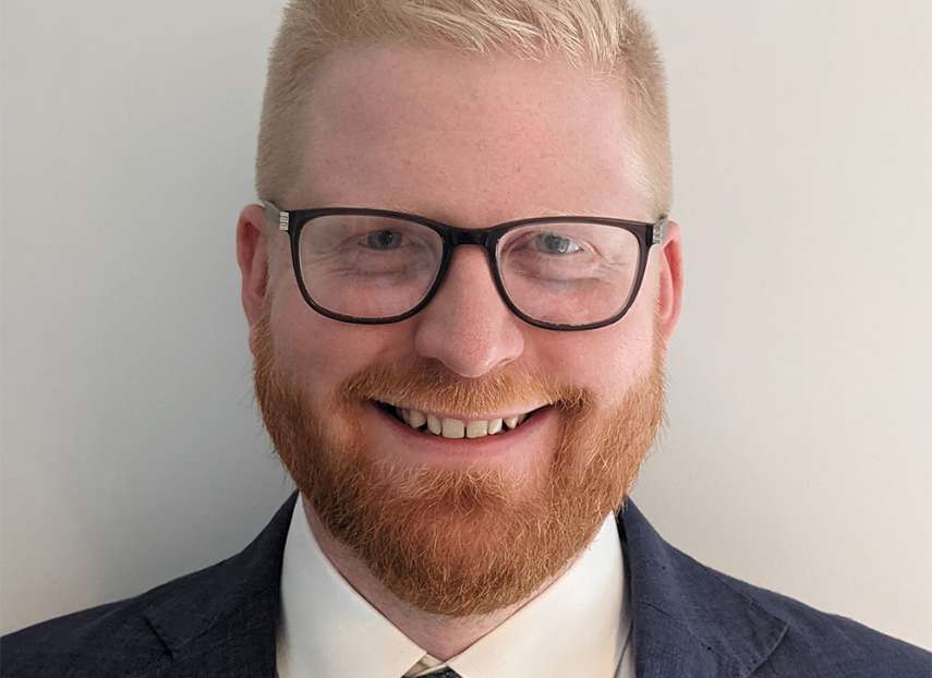 A smiling man with blonde hair and a red beard. He is wearing glasses and a suit. Chris Wagner, an Associate Director of Finance for Contracts and Procurement within the Lewisham and Greenwich NHS Trust, London.