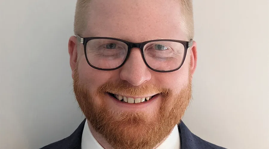 A smiling man with blonde hair and a red beard. He is wearing glasses and a suit. Chris Wagner, an Associate Director of Finance for Contracts and Procurement within the Lewisham and Greenwich NHS Trust, London.