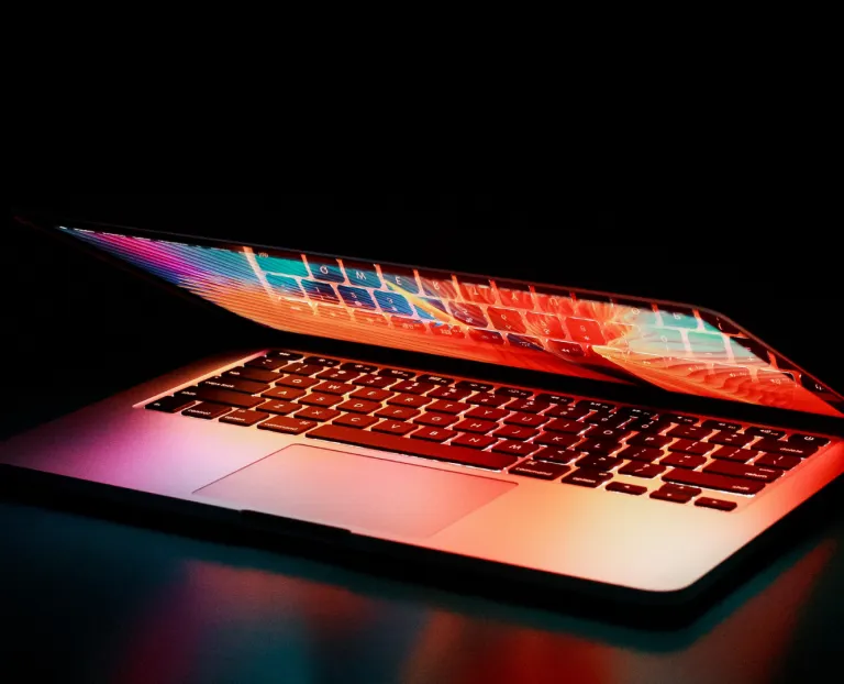 A partially open laptop glowing with neon light