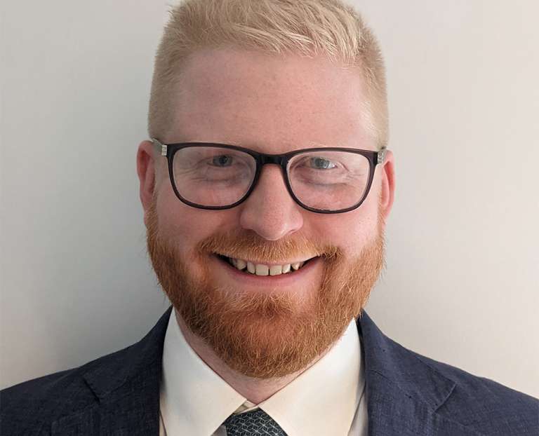 A smiling man with blonde hair and a red beard. He is wearing glasses and a suit. Chris Wagner, an Associate Director of Finance for Contracts and Procurement within the Lewisham and Greenwich NHS Trust, London.